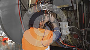 Engineer, technician examines the jet engine with a flashlight.