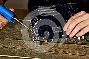 Engineer or technician repair electronic circuit board with soldering iron. Man hands soldiers computer circuit board using solder