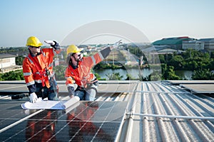 Engineer and technician working on the solar panel on the warehouse roof to inspect the solar panels