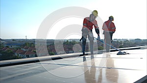 Engineer and technician working on the solar panel on the warehouse roof to inspect the solar panels