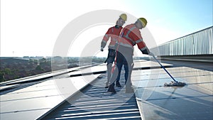 Engineer and technician working on the solar panel on the warehouse roof to inspect the solar panels