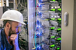 The engineer thinks how to properly connect the wires in the data center server room. A man makes an important decision on the
