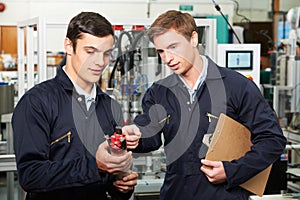 Engineer And Trainee Discussing Component In Factory