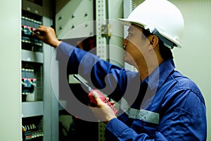 Engineer turning on switch in the electrical cabinet at control room