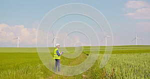 Engineer using digital tablet on wind turbine farm