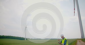 Engineer using digital tablet on wind turbine farm