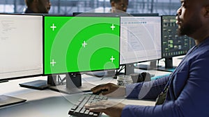 Engineer using green screen computer, working in server farm photo