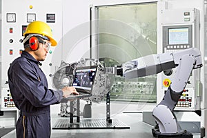 Engineer using laptop computer control automatic robotic hand with CNC machine in automotive industry, Smart factory concept photo