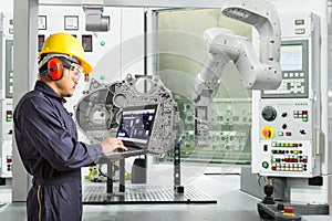 Engineer using laptop computer control automatic robotic hand with CNC machine in automotive industry, Smart factory concept photo