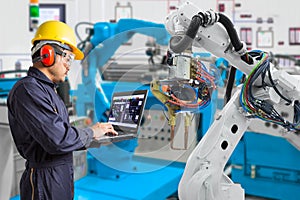 Engineer using laptop computer maintenance automatic robotic hand machine tool in automotive industry, Industry 4.0 concept photo