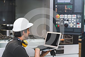 Engineer using laptop computer operating control CNC Machinery at factory