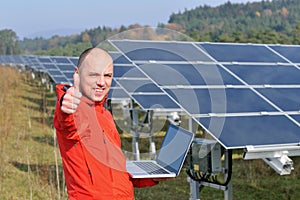 Engineer using laptop at solar panels plant field