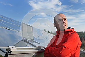 Engineer using laptop at solar panels plant field