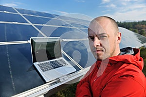 Engineer using laptop at solar panels plant field