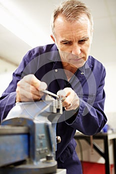 Engineer Using Metal File On Factory Floor