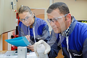 Engineer using pressurised spray female colleague taking notes