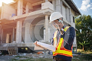 Engineer using smart phone talk with team for checking with blueprints on construction site