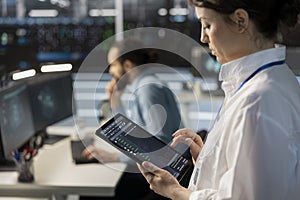 Engineer using tablet in data center, managing servers, running scripts, closeup