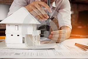 Engineer using vernier caliper to measuring house model