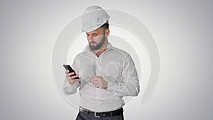 Engineer walking and using smartphone on gradient background.