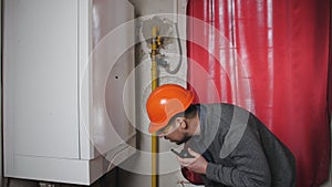 Engineer wearing glasses working in the boiler room,maintenance checking technical data of heating system equipment.