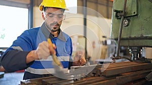 Engineer wearing safety helmet and glasses standing in the production of manufacturing factory. Remove metal chip from the machine
