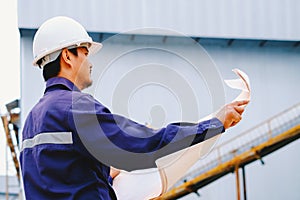 Engineer with white safety helmet holding project plan at construction outdoor site background