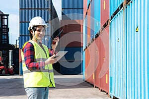 Engineer woman or Foreman manager in container depot working with digital tablet and walkie talkie for control and checking