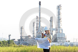 Engineer woman holding blueprint with radio for workers security control at power plant energy and petrochemical industry.