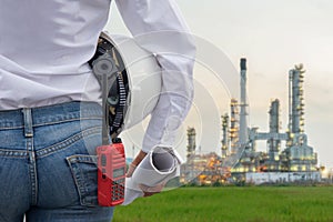 Engineer woman holding white helmet and blueprint with radio for workers security control at power plant