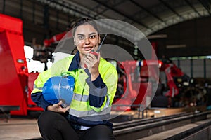 Engineer woman smart female indian worker supervisor with safety suit work in robot metal machinery factory operator radio control