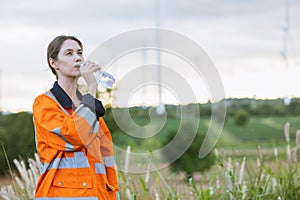 Engineer woman technician standing relax rest drinking clean water after finish service maintenance wind turbine power generator