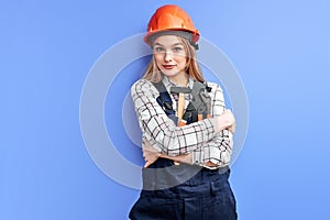 engineer woman wearing orange helmet and blue coverall holding wrench, hammer and other tools