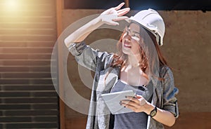 Engineer woman wearing white helmet stand at outdoor holding tablet on site job. Architect women wearing construction hard