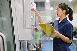 Engineer women control operate CNC industrial machine in metal production workshop. Asian young female industry worker