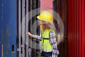 Engineer women wear yellow helmets and reflection shirts working on tablet computers to check inventory details of containers box.