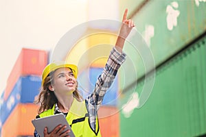 Engineer women wear yellow helmets and reflection shirts working on tablet computers to check inventory details of containers box