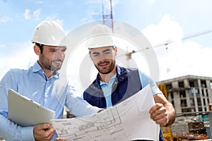 Engineer and worker checking plan on construction site