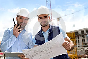 Engineer and worker checking plan on construction site