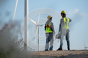 Engineer and worker discussing on a wind turbine farm