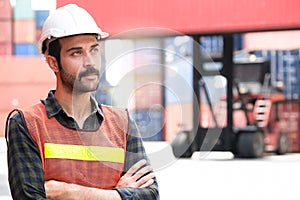 Engineer worker standing in the container yard shipping area and look at the front