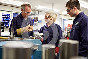 Engineer Working With Apprentices On Factory Floor