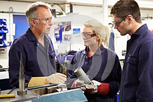 Engineer Working With Apprentices On Factory Floor