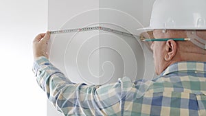 Engineer Working in a Construction Site Use a Tape Measure and Check the Wall Dimensions in a Room
