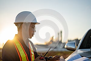 Engineer working with laptop and talking on walkie-talkie at construction site