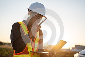 Engineer working with laptop and talking on walkie-talkie at construction site