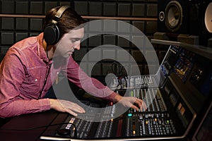 Engineer Working At Mixing Desk In Recording Studio