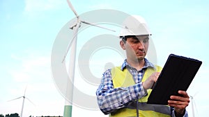 Engineer working with a tablet in front of wind turbines ecological energy industry power windmill