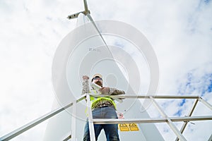 Engineer working at wind turbine site with blueprint