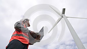 Progressive engineer working with the wind turbine, with the sky as background.